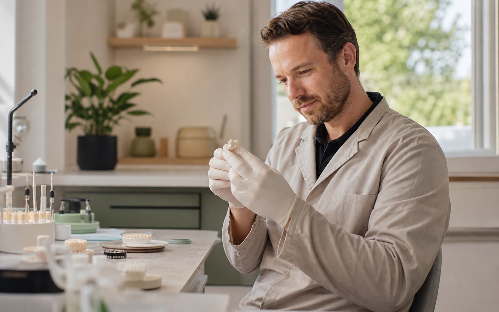 Dental lab technician inspecting a restoration at a clean workbench